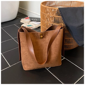 Close-up of a large brown suede tote bag with golden metal swivel clasp for daily commute
