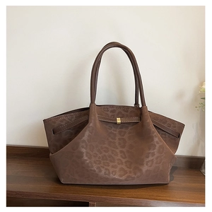Détail d'un sac cabas marron foncé à motif léopard avec boucle dorée sur bois