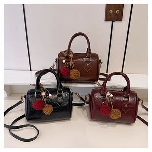 Detail of vintage glossy leather Boston bags in black, brown and burgundy with pendants