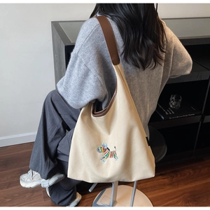 Detail of artistic zebra embroidery on large beige canvas tote with brown leather strap