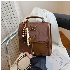 Detail of vintage brown leather backpack with bow metal charm and beaded accessory strap
