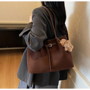 Detail view of large dark brown suede tote bag with a cute teddy bear charm on side