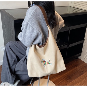Detailed close-up of a beige canvas tote bag with colorful zebra embroidery and leather strap