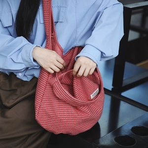 Dettaglio di una borsa tote in nylon a quadretti rossi e bianchi indossata da una modella