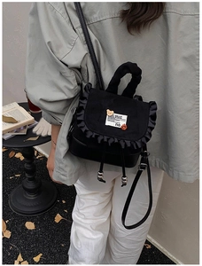 Detail of black mini backpack with ruffled edges and cute bear pins in a vintage setting