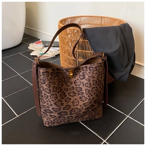 Detailed close-up of leopard print tote bag featuring a metal turn-lock and leather strap