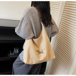 Detail of embroidered zebra pattern on beige canvas hobo bag with brown leather strap