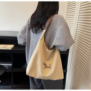Detail of beige canvas tote with colorful zebra embroidery and brown leather trim