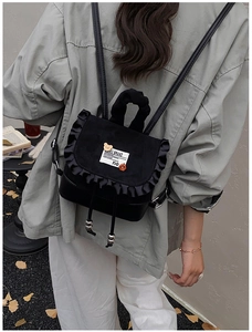Detail of a black mini backpack with ruffled edges and silver sphere drawstring tips