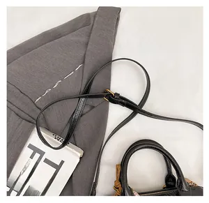 Detail of black lychee grain leather cylinder bag with adjustable strap and gold zipper