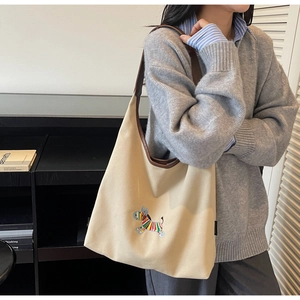 Detail of colorful zebra embroidery and brown leather strap on a beige canvas tote bag