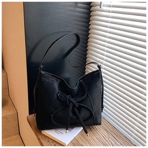 Detail of black suede tote bag with white contrast stitching and bow decoration