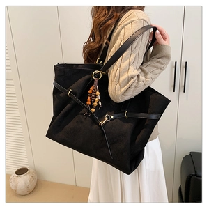 Detail of a large black matte tote bag with vintage wooden beads and metal buckle