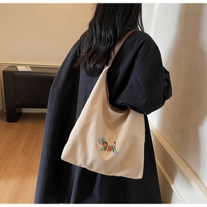 Detailed view of beige canvas tote with colorful zebra embroidery and brown leather straps