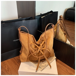 Detail of vintage caramel suede tote bag with stylish knot tassel and mirror reflection