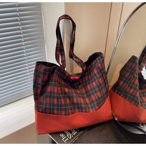 Détail du sac cabas à carreaux rouge et noir avec intérieur spacieux et texture durable