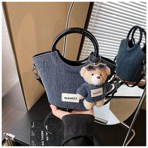 Dettaglio della borsa a secchiello in denim con manico in pelle e ciondolo a forma di orso