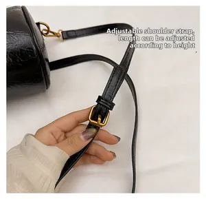 Detail of adjustable black faux leather shoulder strap with gold metal buckle