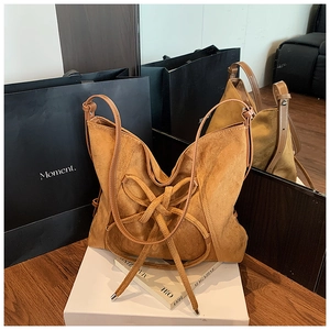 Detailed view of the brown suede tote bag featuring a large decorative bow and strap