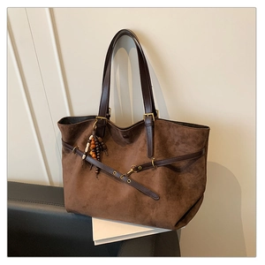 Detail view of large dark brown tote bag with suede texture and wooden bead pendant