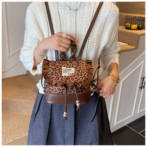 Detailed view of leopard print mini backpack with ruffle edge and brown leather trim