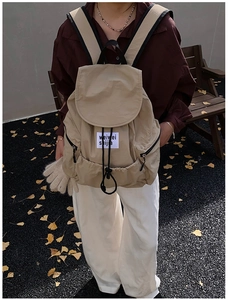 Detailed view of khaki nylon backpack featuring drawstring closure and flap on hiker