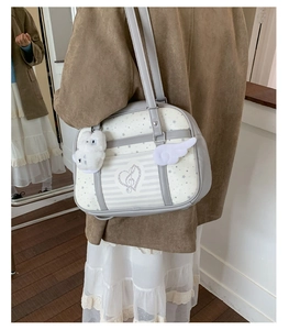 Detail of star pattern shoulder bag with plush pom-pom and wing pendant accessories