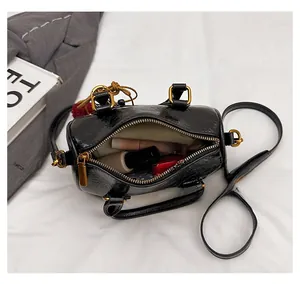 Top view of open black cylinder bag showing interior space with cosmetics and gold details