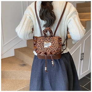Detail of leopard print mini backpack featuring ruffled leather trim and slim brown straps