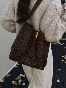 Large leopard print tote bag with gold twist-lock closure shown in an autumn street setting