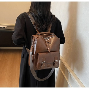 Detailed side view of vintage dark brown PU leather backpack with dual metallic zippers