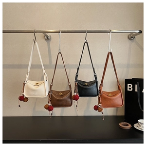 Detail of multi-colored retro crossbody pillow bags with gold locks and pompom charms