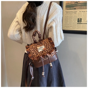 Detailed back view of a mini leopard print backpack with brown leather trim and ruffles