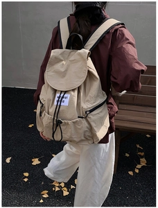 Detail of khaki nylon backpack featuring a drawstring closure and a minimalist fabric label