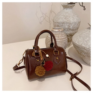 Close-up of retro brown Boston bag with ethnic pom-pom charm and vintage hardware