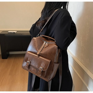 Detail of dark brown vintage faux leather backpack with metallic buckle and stud accents
