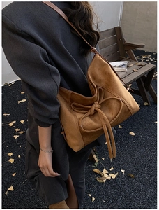 Brown suede shoulder bag with bow detail shown in a vintage autumn outdoor setting