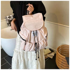 Pink nylon backpack with drawstring closure and front label shown in a hand-held shot