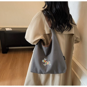 Grey canvas tote bag with zebra embroidery and brown leather trim shown on model
