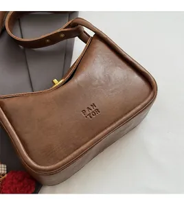 Detail shot of brown crescent leather bag with PAN TOR logo and golden twist lock