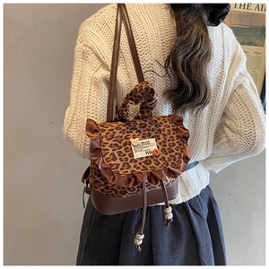 Detail of leopard print mini backpack with ruffle trim and cute bear charm on model