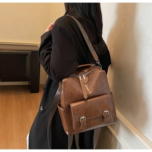 Detail view of brown vintage leather backpack worn by a model in minimalist interior setting