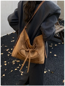 Detail of caramel suede tote bag featuring a leather bow knot decoration and reinforced seams