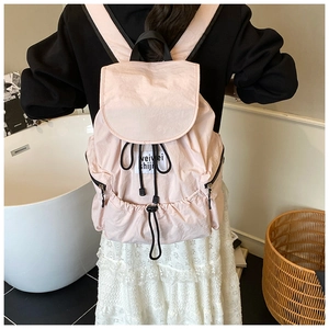 Detail of pink nylon backpack featuring drawstring closure and side black zipper pockets