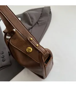 Detail of brown leather handbag featuring a golden swivel lock and reinforced rivets