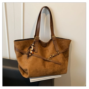 Detail of suede tote bag with wooden bead charm and adjustable leather shoulder strap