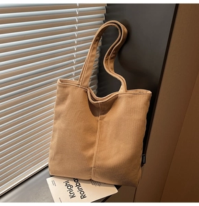 Detailed macro view of khaki corduroy tote bag showing ribbed texture and black side label