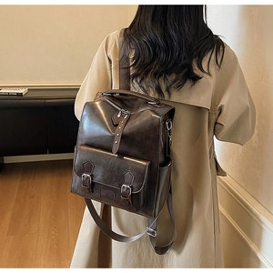 Detail of vintage dark brown PU leather backpack with decorative buckle pocket on model