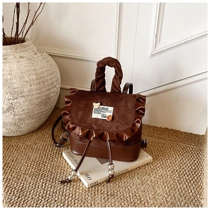 Detail of deep brown velvet mini backpack with ruffle trim and cute bear floral accessories