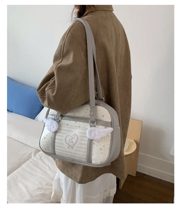 Dettaglio borsa uniforme JK con ali di peluche e motivi a stelle su ecopelle grigio bianca